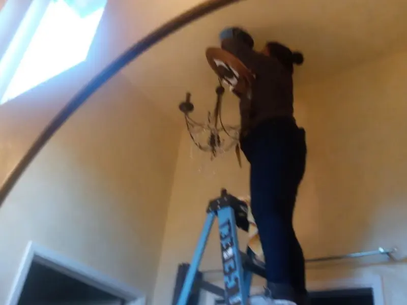 Electrician installing a chandelier in a Sioux City residence